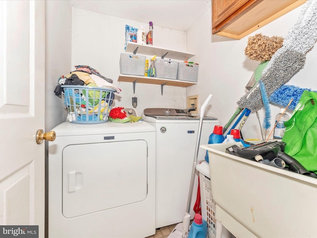 clothes washing area with cabinets and washing machine and clothes dryer