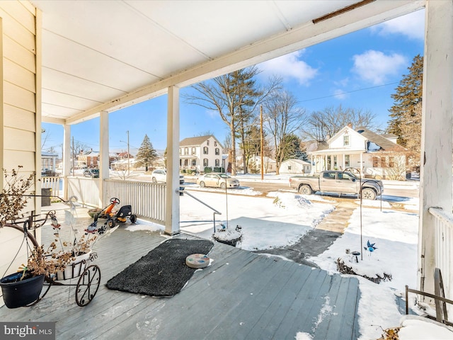 snow covered deck featuring covered porch