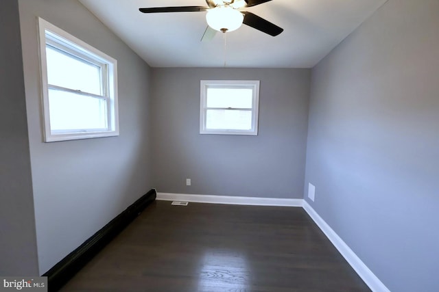 unfurnished room featuring plenty of natural light, ceiling fan, and dark hardwood / wood-style flooring