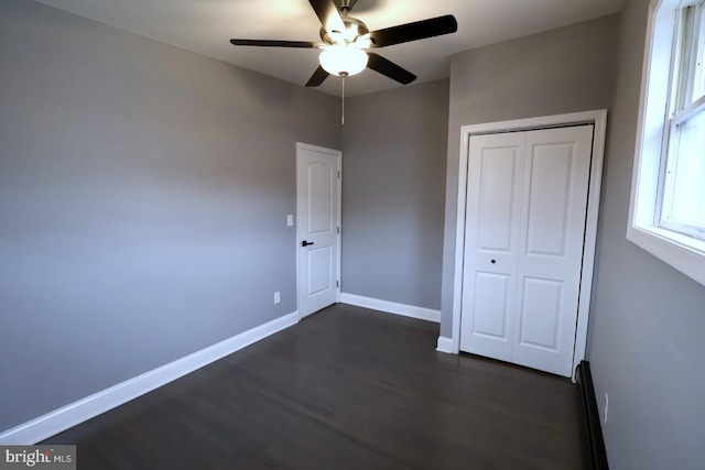 unfurnished bedroom with dark hardwood / wood-style floors, ceiling fan, and a closet