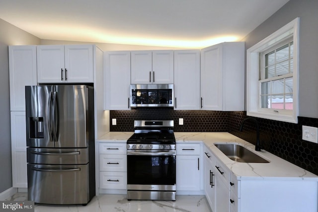 kitchen with stainless steel appliances, white cabinetry, lofted ceiling, and sink