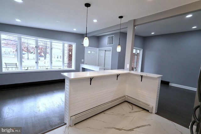 kitchen featuring a kitchen bar, hardwood / wood-style flooring, and hanging light fixtures