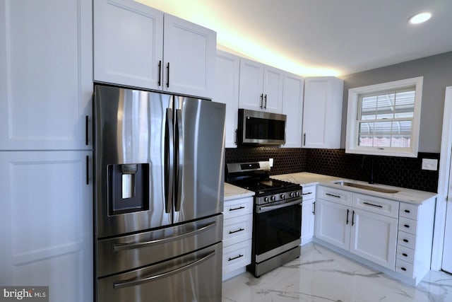 kitchen with white cabinets, backsplash, light stone countertops, and stainless steel appliances