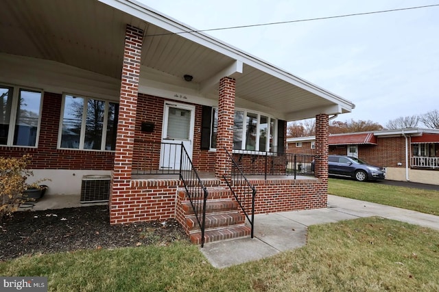 view of front of house featuring covered porch, central AC unit, and a front lawn