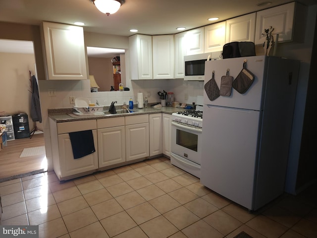 kitchen featuring decorative backsplash, white appliances, and white cabinetry