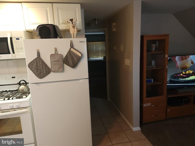 kitchen featuring white cabinets, light tile patterned floors, and white appliances