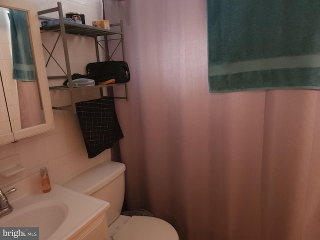 bathroom with vanity, backsplash, toilet, and tile walls