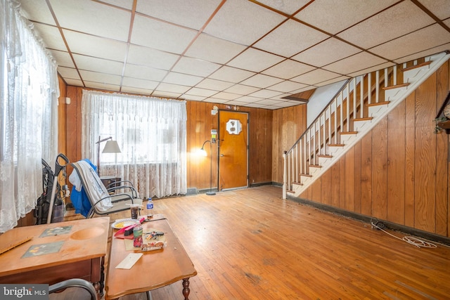 foyer with wood-type flooring, a drop ceiling, and wooden walls