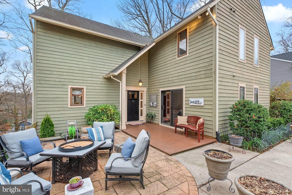 back of house featuring a wooden deck and an outdoor living space with a fire pit