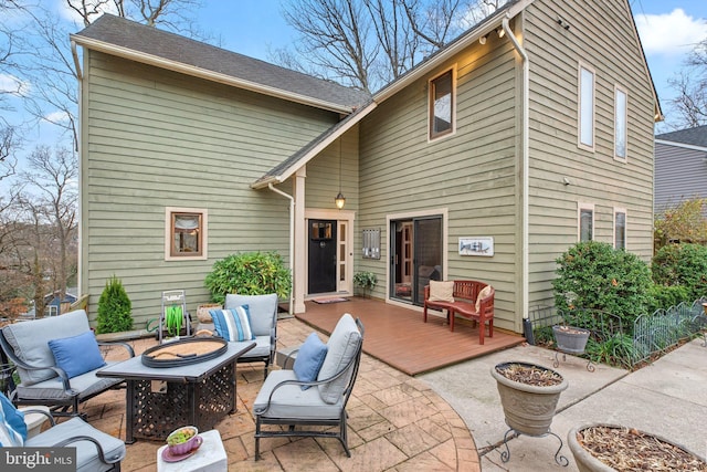 back of house featuring a wooden deck and an outdoor living space with a fire pit