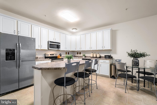 kitchen featuring a kitchen bar, stainless steel appliances, white cabinetry, and a kitchen island