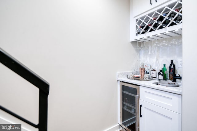 bar with white cabinets, light stone counters, sink, and wine cooler