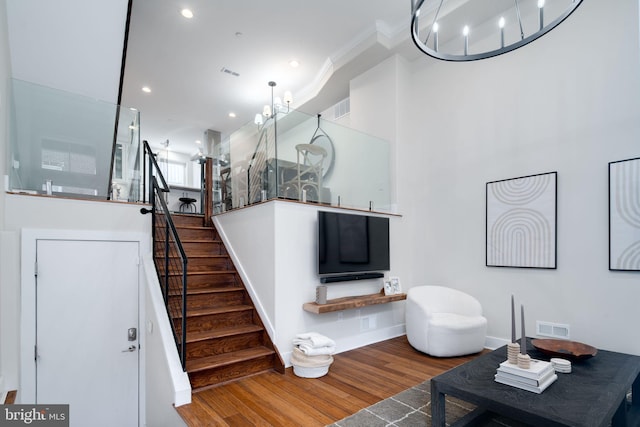 stairs with hardwood / wood-style floors, an inviting chandelier, and ornamental molding