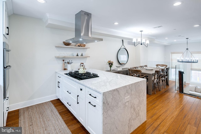 kitchen featuring island exhaust hood, black gas stovetop, wood-type flooring, pendant lighting, and white cabinets