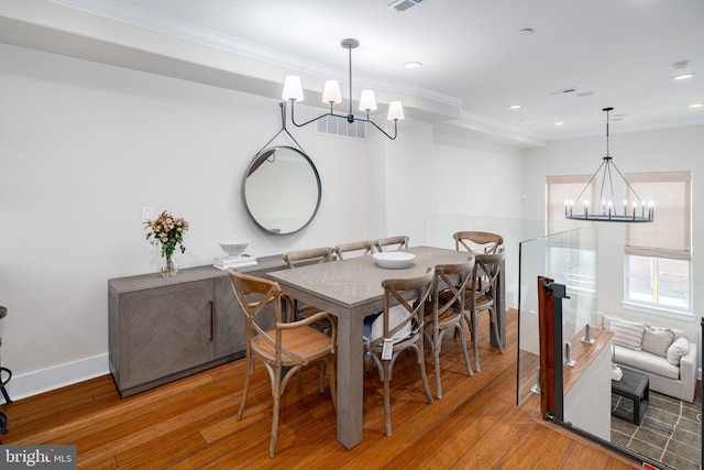 dining space featuring hardwood / wood-style floors, an inviting chandelier, and crown molding