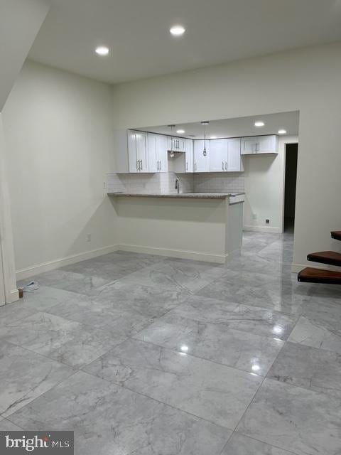 kitchen with sink, white cabinetry, kitchen peninsula, and tasteful backsplash