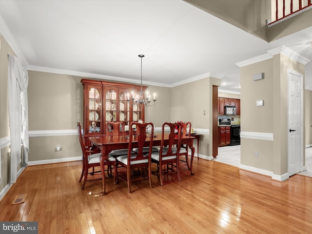 dining room with light wood-type flooring, crown molding, and a notable chandelier