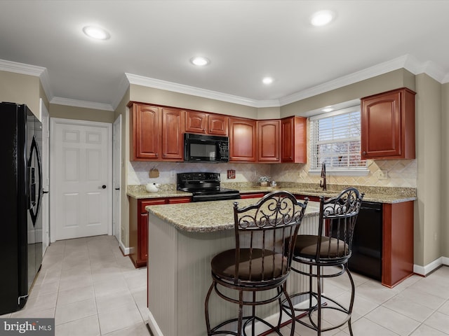 kitchen featuring light stone countertops, a kitchen island, crown molding, and black appliances