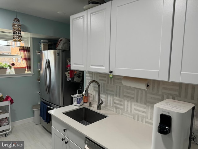 kitchen with decorative backsplash, stainless steel fridge, sink, white cabinets, and light tile patterned flooring