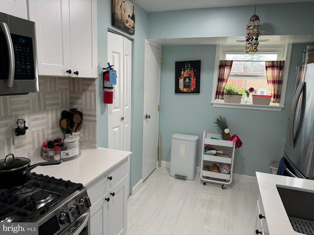 kitchen featuring white cabinets, appliances with stainless steel finishes, and decorative light fixtures