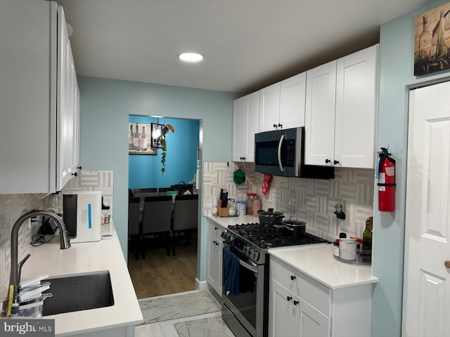 kitchen featuring decorative backsplash, sink, white cabinets, and appliances with stainless steel finishes