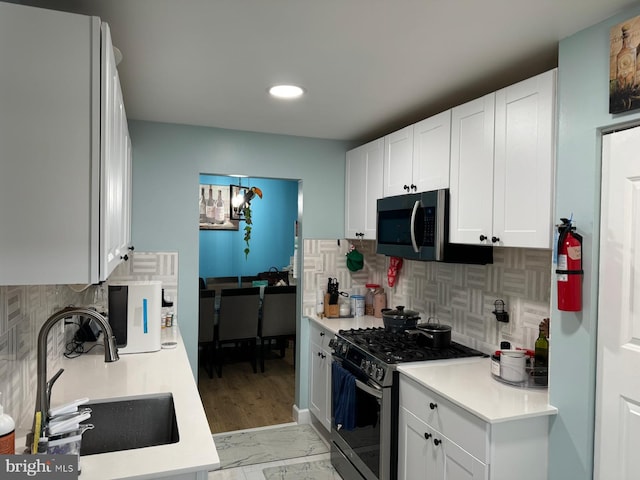 kitchen featuring sink, white cabinetry, stainless steel appliances, and tasteful backsplash