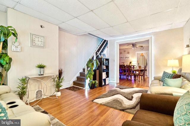 living room with hardwood / wood-style floors, a paneled ceiling, and ceiling fan