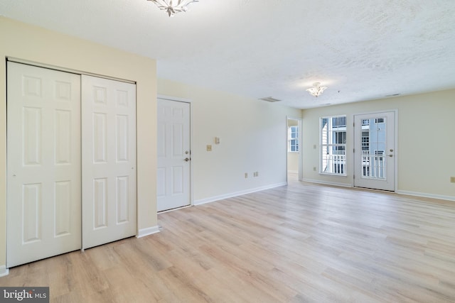 interior space with a textured ceiling, light hardwood / wood-style flooring, and multiple closets