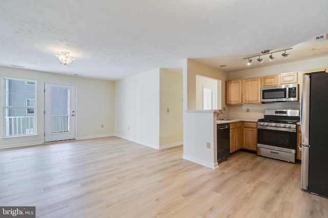 kitchen featuring light brown cabinets, stainless steel appliances, a textured ceiling, and light hardwood / wood-style floors