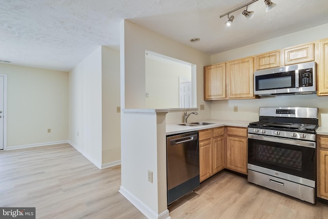 kitchen with sink, light hardwood / wood-style floors, a textured ceiling, and appliances with stainless steel finishes