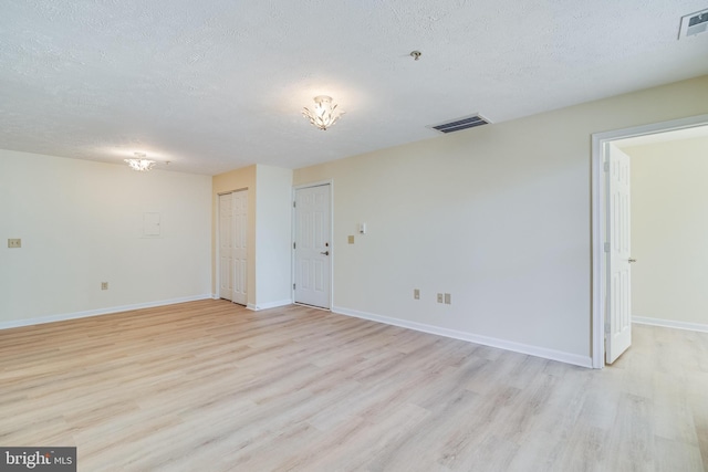 unfurnished room with light hardwood / wood-style flooring and a textured ceiling