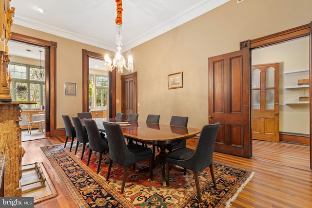 dining area featuring an inviting chandelier, ornamental molding, and light hardwood / wood-style flooring