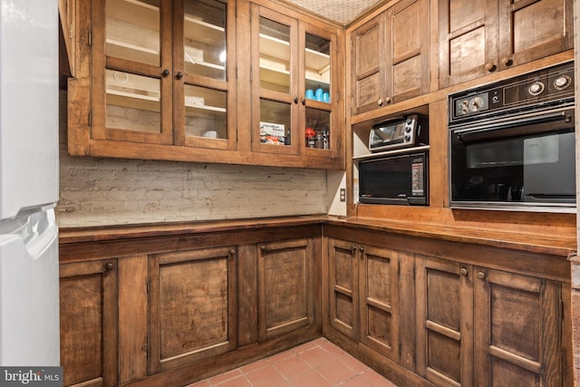 kitchen with black appliances, light tile patterned flooring, butcher block counters, and tasteful backsplash