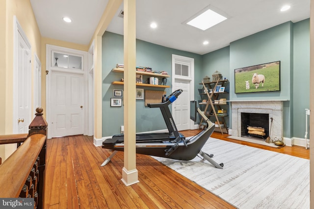 exercise room with hardwood / wood-style flooring and a high end fireplace