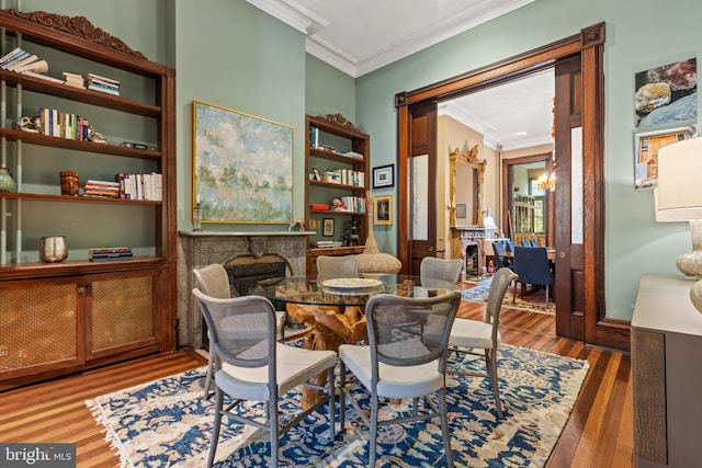 sitting room with a stone fireplace, dark hardwood / wood-style flooring, and crown molding