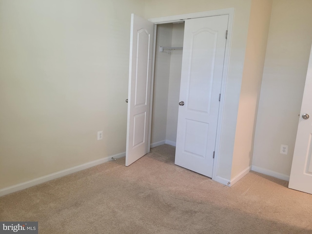 unfurnished bedroom with light colored carpet and a closet