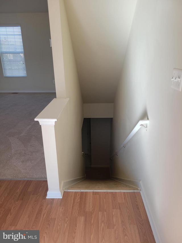 stairs featuring wood-type flooring and vaulted ceiling