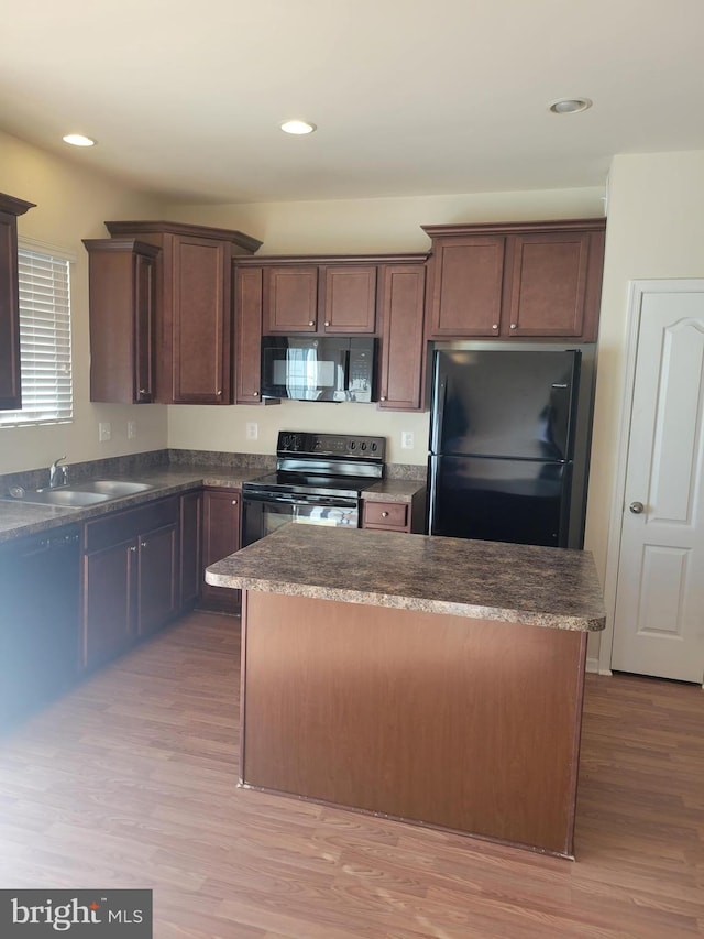 kitchen featuring light wood-type flooring, dark brown cabinets, sink, black appliances, and a kitchen island