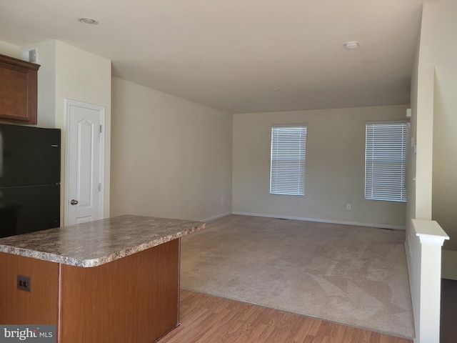 kitchen featuring light wood-type flooring and black fridge