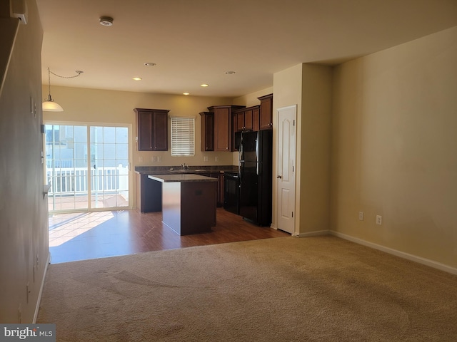 kitchen with sink, a center island, hanging light fixtures, dark carpet, and black appliances