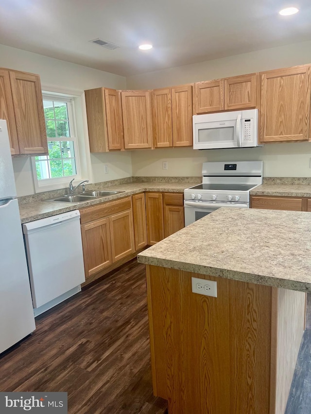 kitchen with light brown cabinets, white appliances, dark hardwood / wood-style floors, and sink