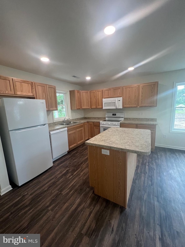 kitchen with sink, a center island, dark hardwood / wood-style floors, and white appliances