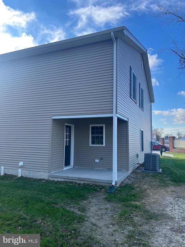 rear view of property with a patio, cooling unit, and a lawn