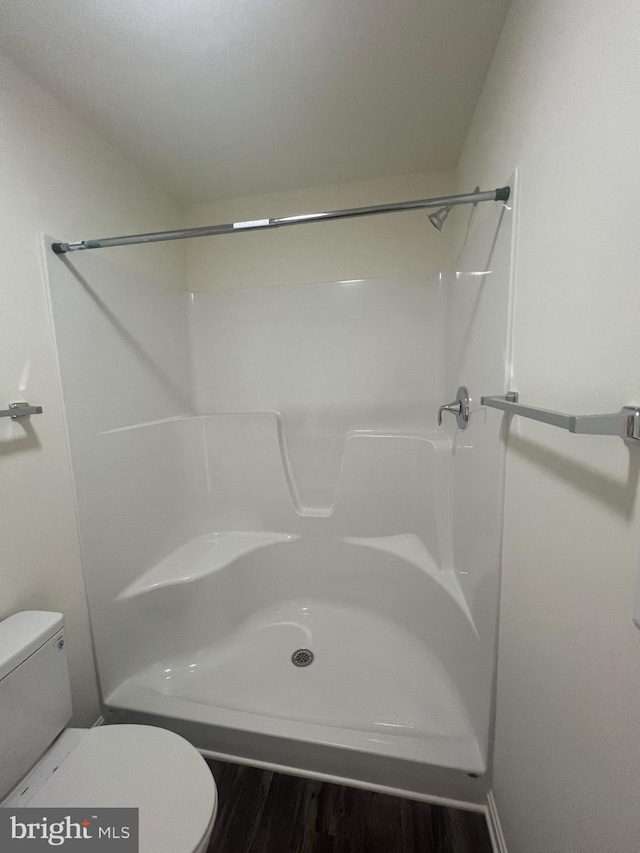 bathroom with a shower, toilet, and hardwood / wood-style flooring