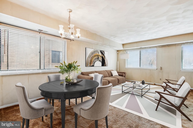 carpeted dining area featuring a healthy amount of sunlight and an inviting chandelier