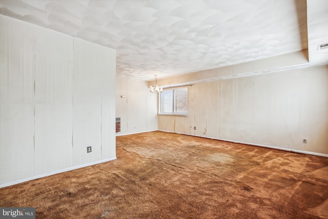 carpeted spare room with a chandelier