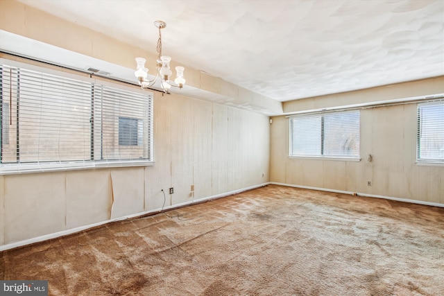 carpeted spare room featuring a chandelier