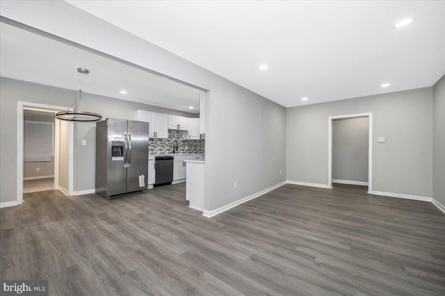 kitchen featuring dark hardwood / wood-style floors, pendant lighting, decorative backsplash, white cabinets, and appliances with stainless steel finishes