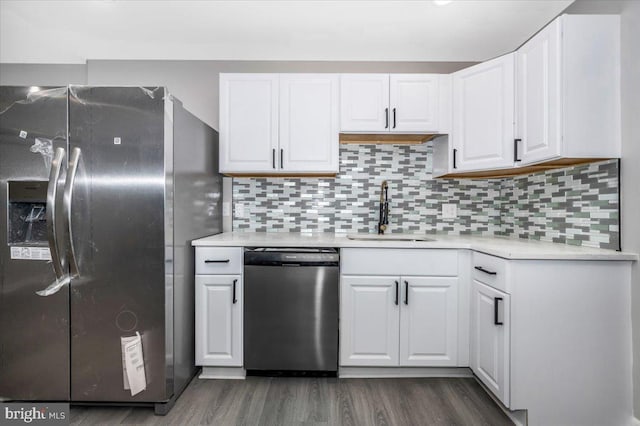 kitchen with appliances with stainless steel finishes, backsplash, dark wood-type flooring, sink, and white cabinetry