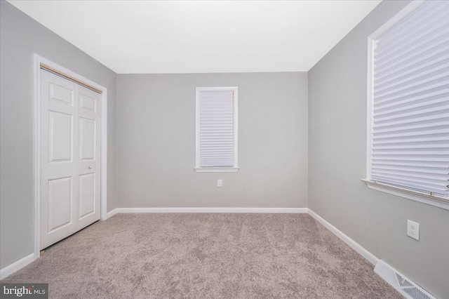 unfurnished bedroom with light carpet and a closet